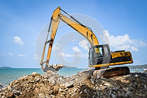 Backhoe loader digger excavator stone working construction site on the beach sea ocean