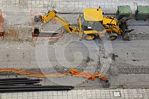 Backhoe loader digging in city street