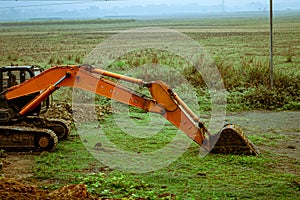 A backhoe loader excavator digger, a heavy industrial vehicle on a green agricultural field