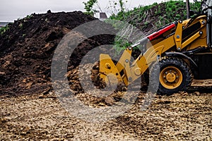 Backhoe loader planning and cutting clay ground at eathmoving works in construction site