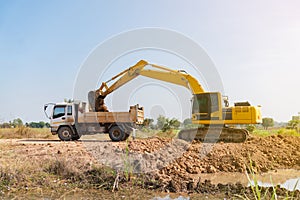 Backhoe loader soil from the ground up to dump truck photo