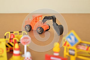 Backhoe loader toy with blurred construction site equipments