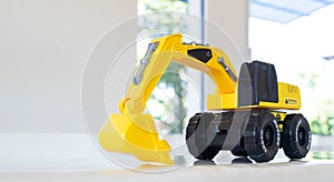 Backhoe loader, yellow construction toy vehicle with articulated parts built with sturdy plastic is placed on a table