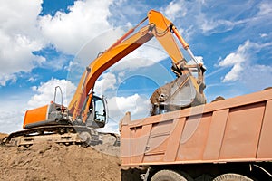 Backhoe loading soil into dump truck body