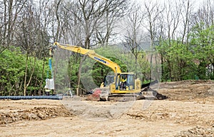 Backhoe Lowering Concrete Block into Drainage Trench