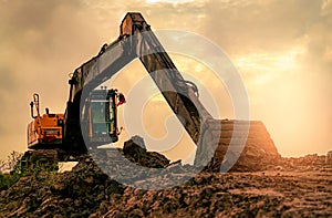 Backhoe parked at construction site after digging soil. Bulldozer on sunset sky and clouds background. Digger after work. Earth