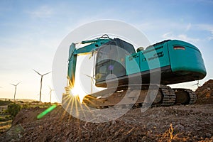 Backhoe and wind turbines that are generating electricity in the background  the concept of sustainable resources  Beautiful sky