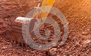 Backhoe working by digging soil at construction site. Bucket of backhoe digging soil. Crawler excavator digging on dirt. Closeup