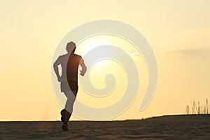 Backlight of a jogger running on the beach