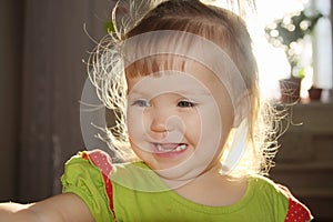 Backlight portrait of baby girl smiling,tousled hair of happy talking child