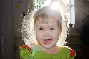 Backlight portrait of baby girl smiling,tousled hair of happy talking child, sunset through window