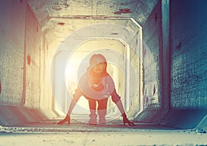 Backlight of a teenager depressed sitting inside a dirty tunnel