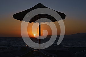 Beach umbrella at sunset with setting sun photo