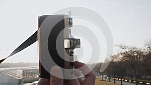 Backlit close-up shot, hand holding vintage film camera, sunset Paris Eiffel Tower is seen in viewfinder slow motion.