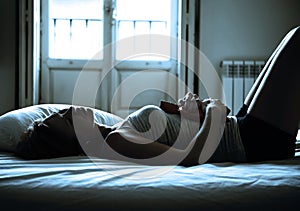 Backlit dramatic light of young beautiful woman suffering period pain in bed photo