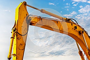 Backlit excavator on an industrial site against the background of the evening sky. Construction machinery for earthworks