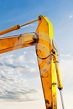 Backlit excavator on an industrial site against the background of the evening sky. Construction machinery for earthworks
