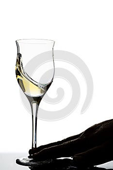 Backlit hand of a man moving a glass of white wine. White background. Concept of movement, elegance, taste