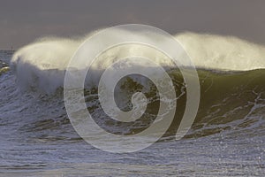 Backlit stormy wave spray at sunset