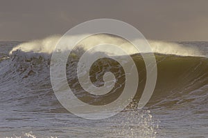 Backlit stormy wave spray at sunset