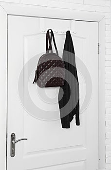 Backpack and clothing hanging on wooden door