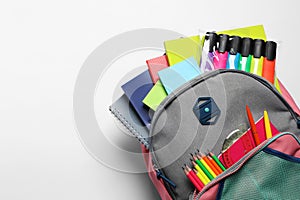 Backpack with different school stationery on white background, top view. Space for text