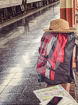 Backpack, hat, cellphone and map on bench at the station.