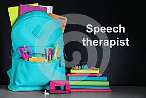Backpack with school stationery and text Speech Therapist on chalkboard