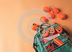 Backpack with school supplies and Halloween pumpkin lights on orange background.Education and Halloween concept