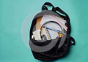 Backpack with stationery on blue background