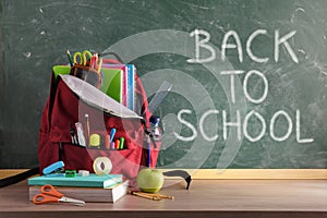 Backpack on table and blackboard with back to school background