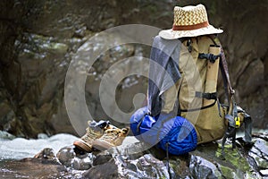 Backpack with travel equipment rests on a rock.