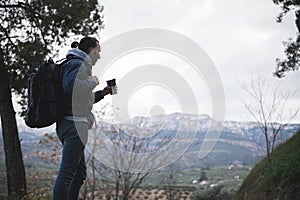 Backpacked male traveler drinking coffee while hiking in mountains. People. Travel. Active tourism and trekking concept