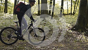 Backpacked man rides bicycle in the forest