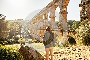 Backpacker astonished by ancient roman aqueducts. El Pont del Diable in Tarragona, Spain.