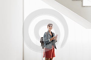 Backpacker caucasian woman at train station using mobile phone app while waiting. Travel concept