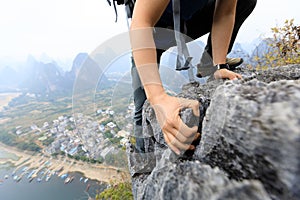 Backpacker climbing rock on mountain top cliff edge