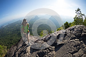Backpacker climbing to mountain top on cliff edge