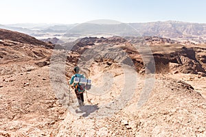 Backpacker descending hiking mountain ridge stone desert landscape