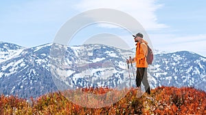Backpacker dressed bright orange jacket walking by the touristic path using trekking poles in Mala Fatra mountain range, Slovakia
