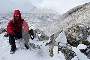 Backpacker dressed in red coat and polarizing spectacles resting on his way to Everest Base camp,Gorakshep, Nepal photo