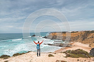 Backpacker enjoys his hike along the Fisherman Trail, Portugal. View of Alteirinhos Beach near Zambujeira do Mar, Odemira region.