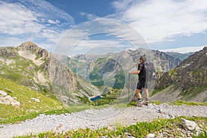 Backpacker hiking on footpath and looking at expansive view from the top. Summer adventures and exploration on the Italian French