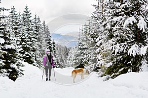 Backpacker hiking walking in winter forest with dog