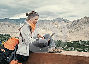 Backpacker with laptop sits on the top view point under mountain