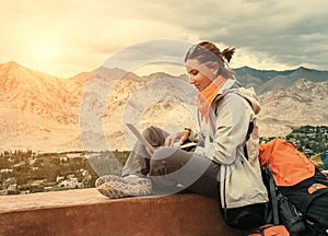 Backpacker with laptop sits on the top view point under mountain