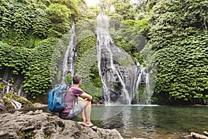 Backpacker looking at waterfall in Bali, tourism