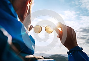 Backpacker man looking at bright sun through polarized sunglasses  enjoying mountain landscape. Eye & Vision Care human health