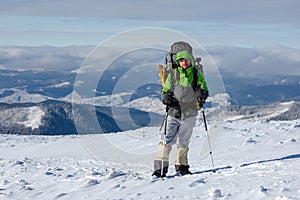 Backpacker man is posing in winter mountains