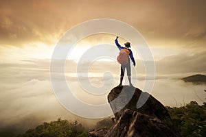 Backpacker man raise hand up on top of mountain with sun sky